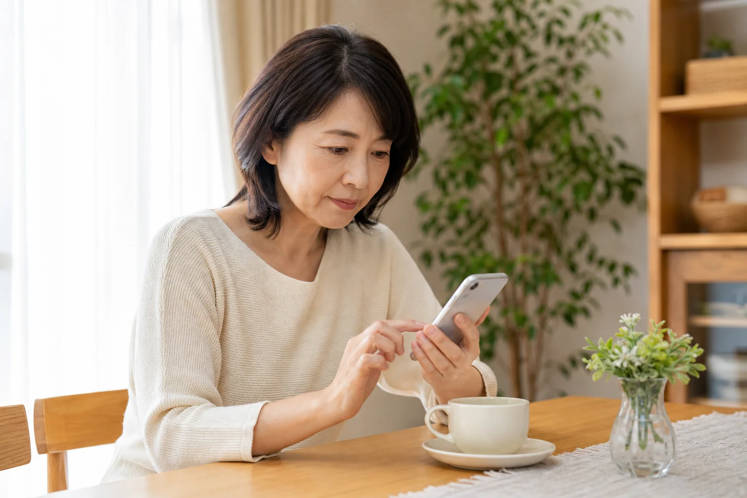 自宅のダイニングでスマホで求人を検索・確認する50代の様子
