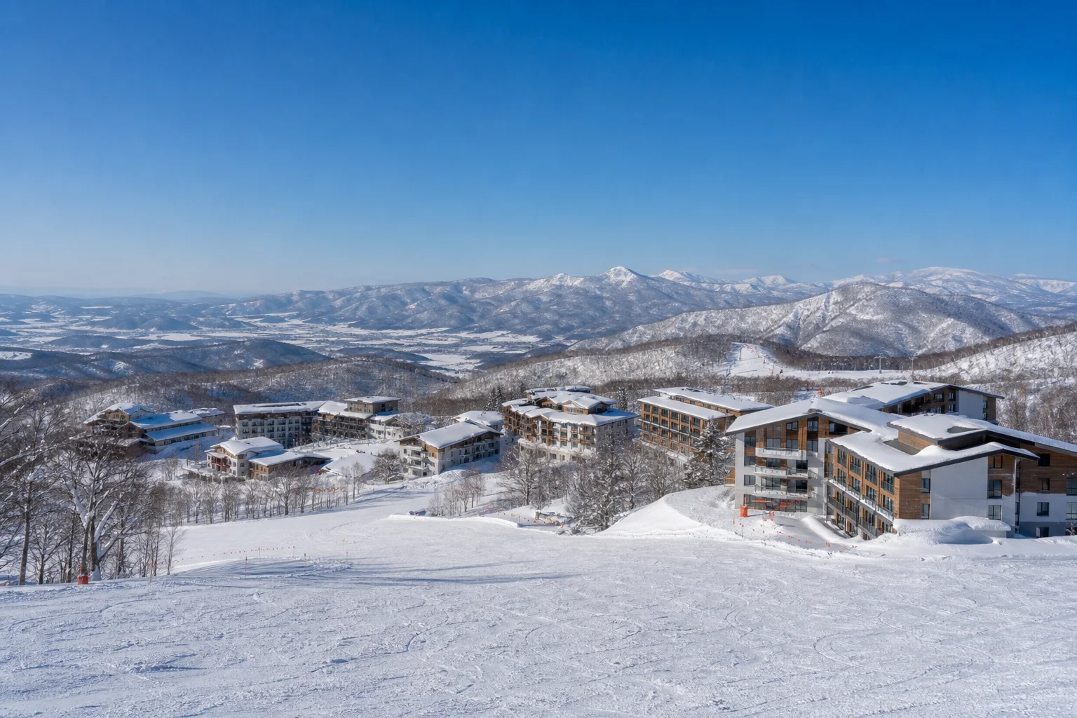 ニセコのスキーリゾートエリアを遠望するパノラマ。雪山と広がるゲレンデ、ホテル群が見える冬晴れの風景
